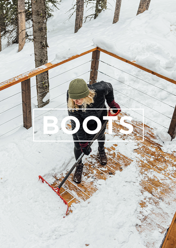 woman wearing snow boots shoveling snow